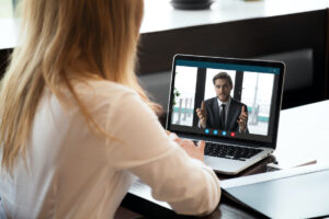 Back view of female employee talk on video call with male colleague or business partner, woman worker communicate online speak on Webcam, have web conference with coworker from home office